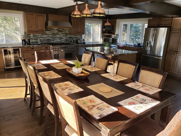 A spacious kitchen with wooden cabinets, stainless steel appliances, and a large dining table set for six. - Beautiful waterfront cottage (with hottub), in the heart of Muskoka. (Huntsville)