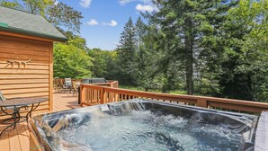 Un jacuzzi en una terraza de madera con vistas a un bosque.