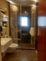 Een moderne badkamer met een douchecabine van glas, een toilet en een wastafel.