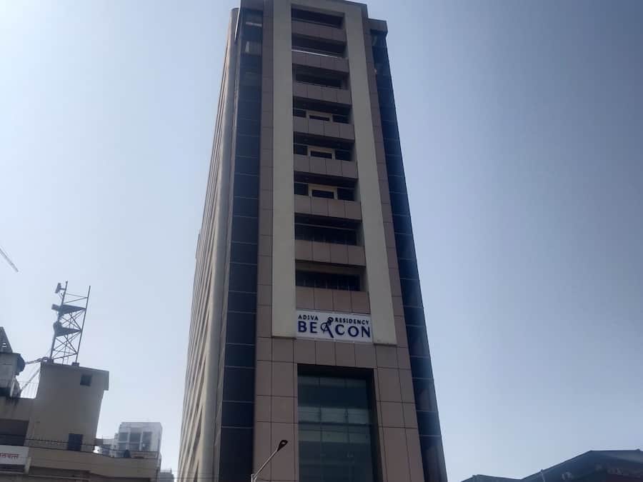 Un edificio alto con el letrero "ADIVA RESIDENCY BEACON" en la fachada.