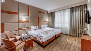 Una habitación de hotel con una cama grande, un escritorio con una computadora portátil, una silla y un televisor.