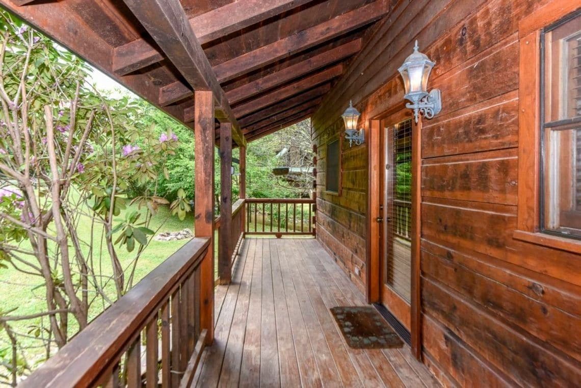 Un portico in legno con ringhiera, una porta con finestra e un lanterne.