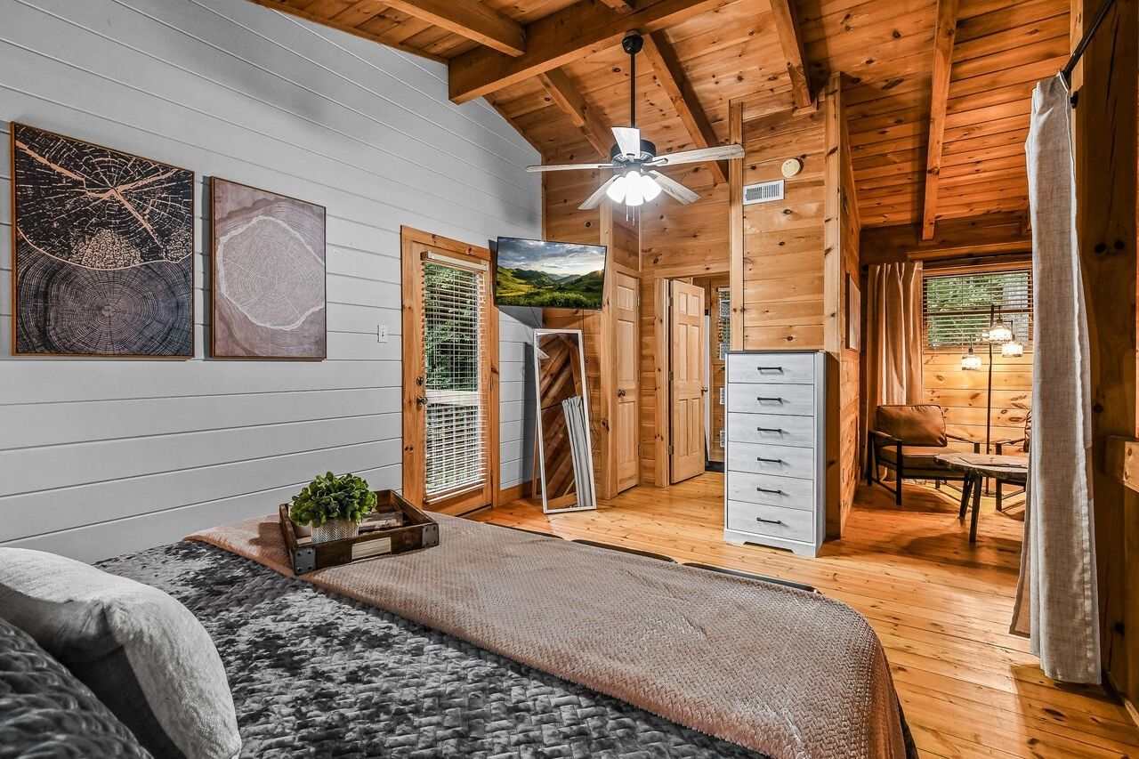 Ein Zimmer mit einem Bett, einem Schreibtisch, einem Stuhl, einem Deckenventilator und Kunstwerken an der Wand.
