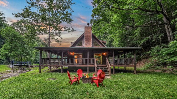 A cabin with a covered porch, a fire pit, and red chairs. - Willow Creek 2 Bedroom Cabin by RedAwning (Townsend)