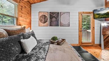 Um quarto aconchegante com uma cama, almofadas, um suporte com uma planta e obras de arte na parede.