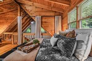 A cozy wooden interior with a sofa, curtains, and a window with blinds. - Willow Creek 2 Bedroom Cabin by RedAwning (Townsend)