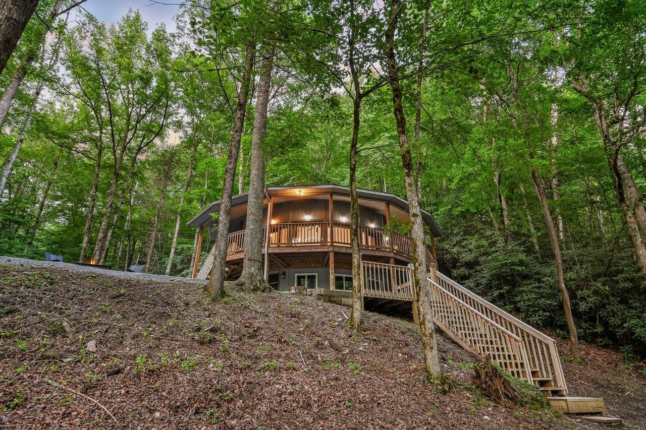 A wooden cabin with a balcony, surrounded by trees.