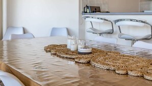 A dining table with a woven placemat, two glasses of water, and a stack of plates. - 69 Shepherd Ave Goolwa South (Goolwa South)