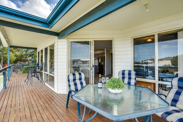 Relax in this serene outdoor space with a glass-top table, potted plant, and comfortable seating.