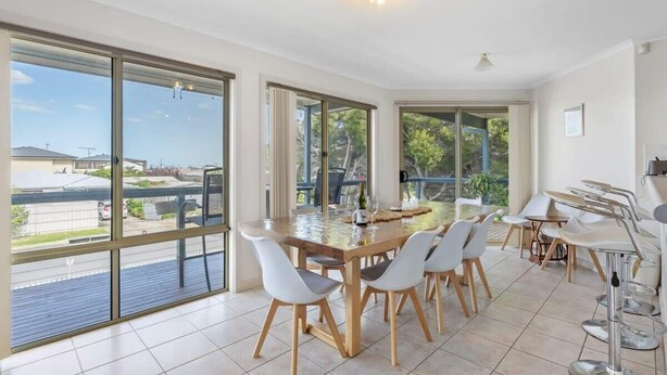 A spacious dining area with large windows, a wooden table, and modern chairs. - 69 Shepherd Ave Goolwa South (Goolwa South)