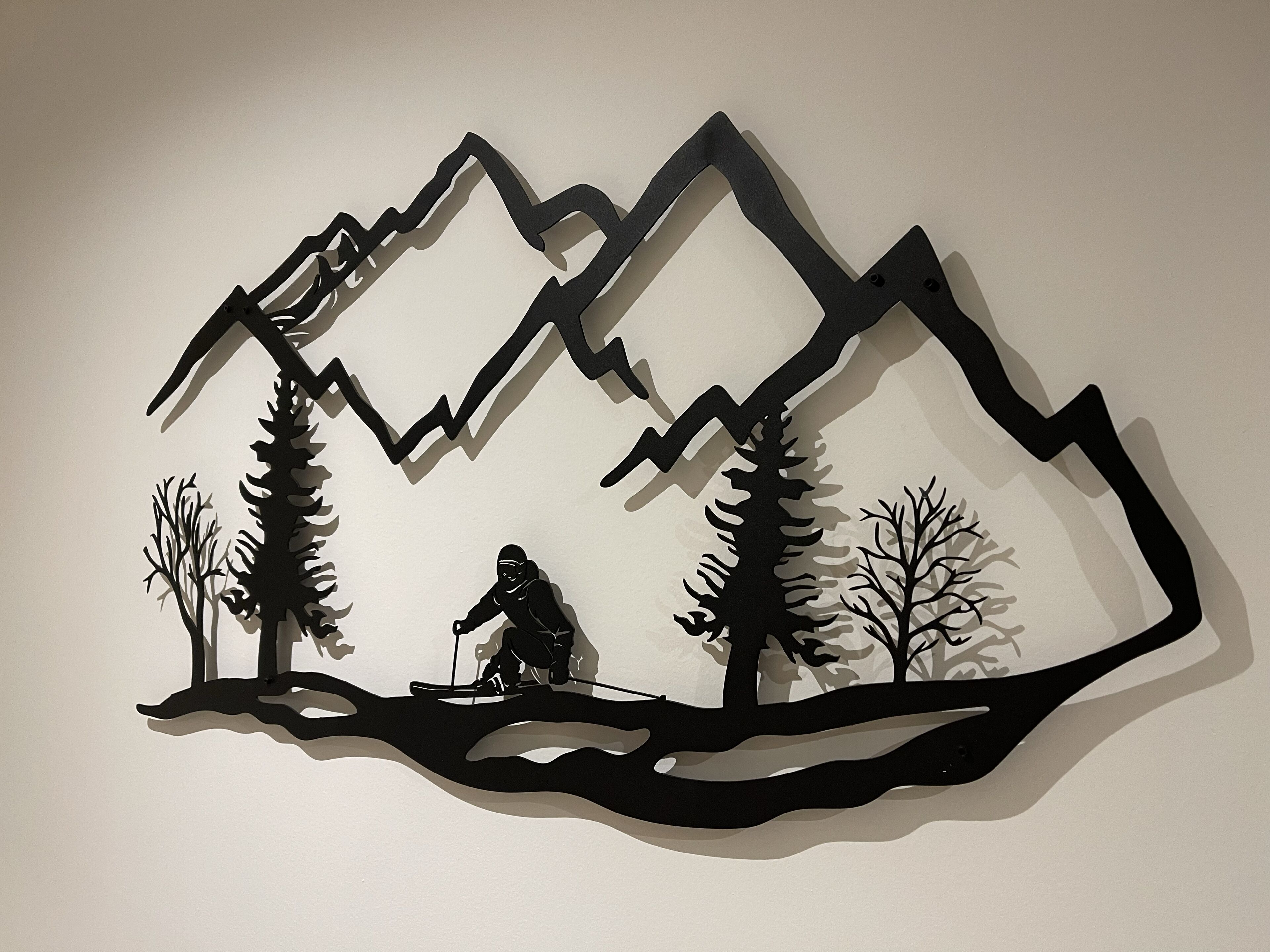 A black silhouette of a mountain landscape with a person fishing.