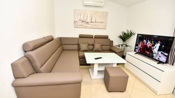 A modern living room with a sectional sofa, a coffee table, and a TV.