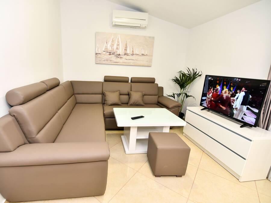Een moderne woonkamer met een modulaire bank, een salontafel en een televisie.