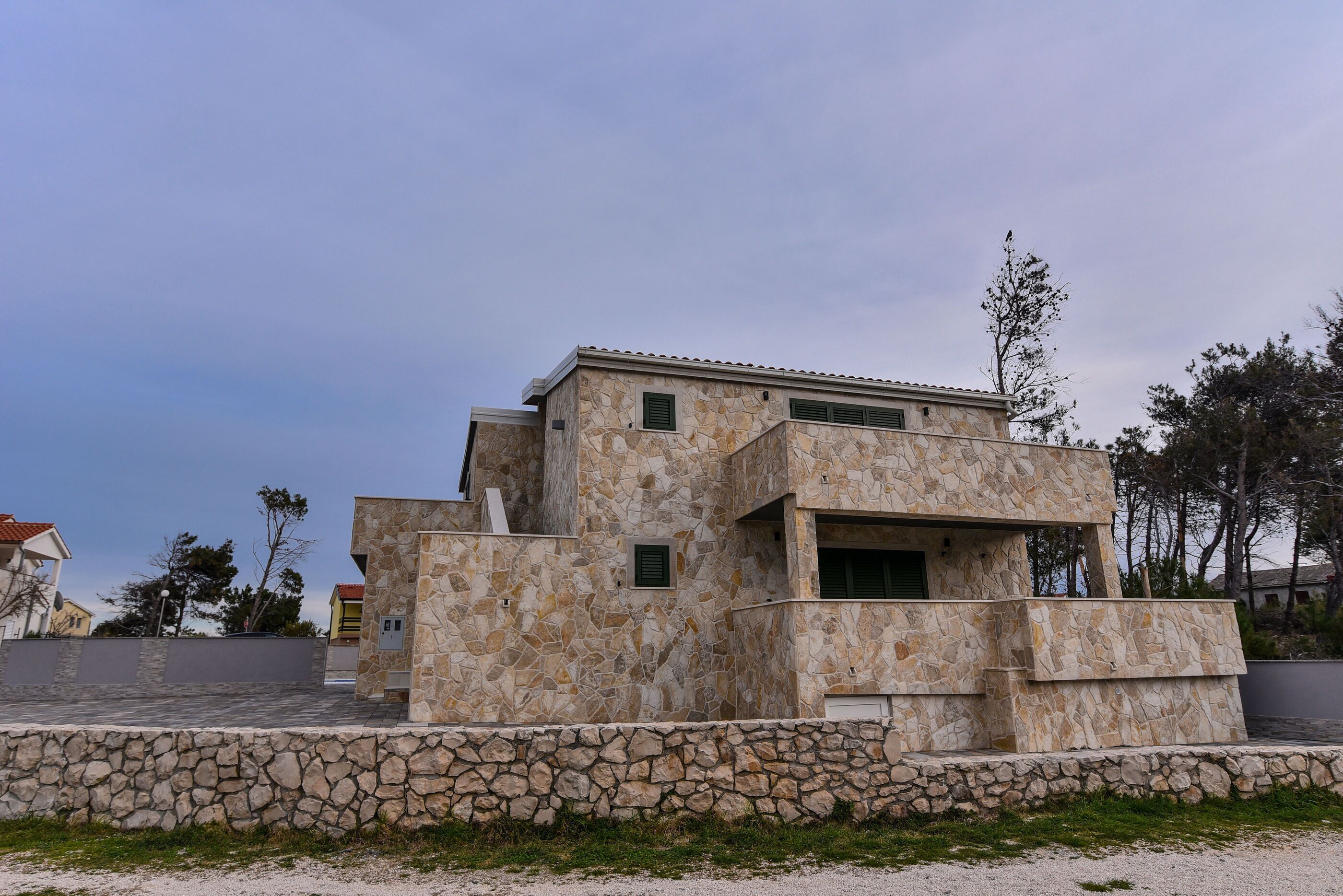 A modern building with a stone facade, multiple windows, and a flat roof.