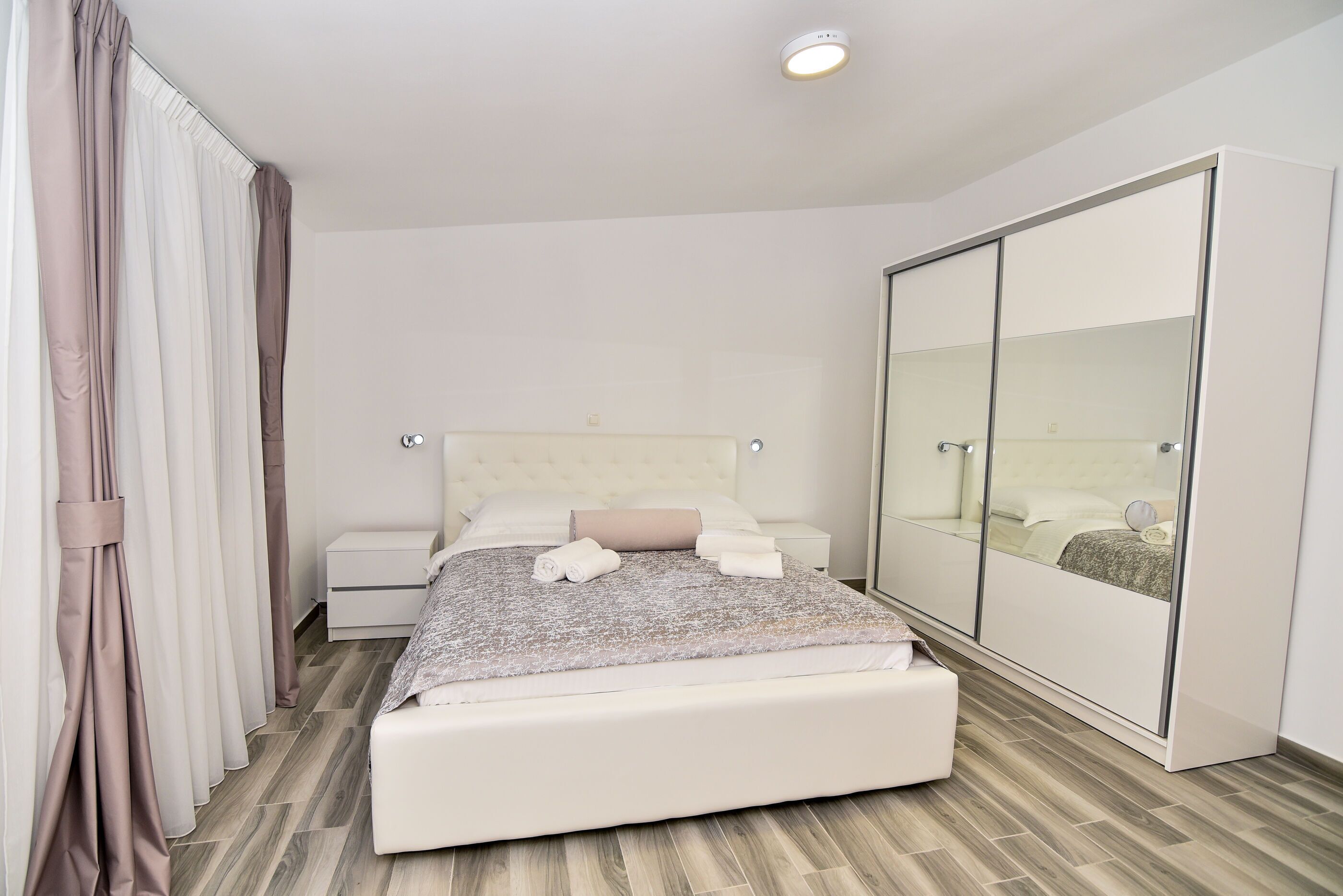 Un dormitorio moderno con una cama grande, un armario y un espejo.