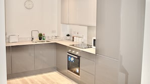 A modern kitchen with a built-in oven, a sink, and a clock on the wall. - Impeccable 1bed Apartment in the Heart Ofgreenford (Greenford)