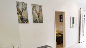 A spacious room with wooden flooring, a bench, and two paintings on the wall.