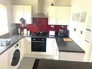 A compact kitchen with a stove, oven, and a washing machine.