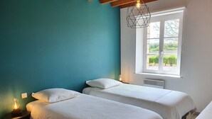 A room with two beds, a window with a view, and a hanging light fixture. - Gîte La Longère Proche de Saint-valéry, au Coeur de la Baie de Somme (Saigneville)