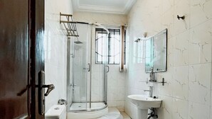 A bathroom with a toilet, sink, and glass shower enclosure.