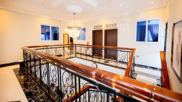 A spacious interior with a grand staircase, a chandelier, and large windows.