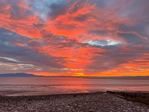A sunset over a calm sea with a rocky shoreline.