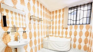 Un baño con lavamanos blanco, bañera y ventana con barrotes.