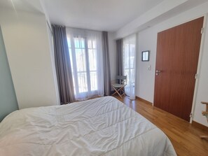 Une chambre à coucher avec un grand lit, une porte en bois et une fenêtre avec des rideaux.