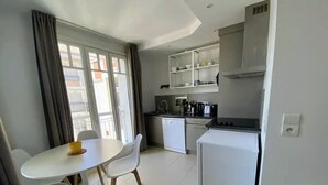 Una cucina compatta con elettrodomestici bianchi, un tavolo da pranzo con sedie e vista dalla finestra.