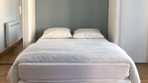 Camera da letto con un letto, due cuscini e un termosifone.