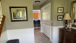 Un couloir avec un banc, une commode et une porte donnant sur la cuisine.