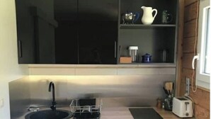 Eine kleine Küche mit Spüle, Toaster und kleinem Kühlschrank.