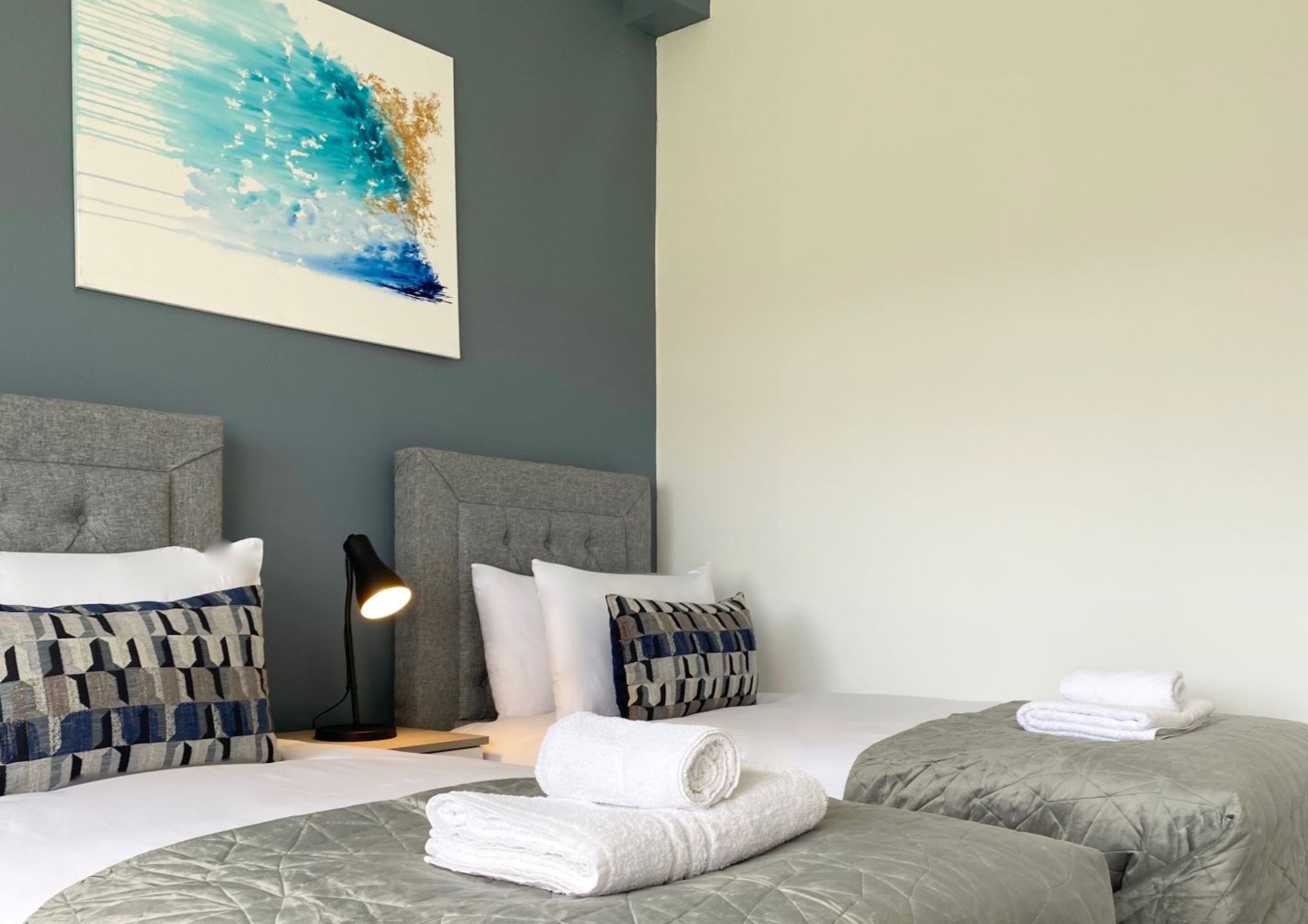 Ein Hotelzimmer mit zwei Betten, einem Nachttisch mit Lampe und einem Bild an der Wand.
