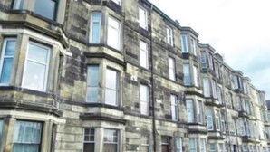 Una hilera de edificios de piedra tradicionales con numerosas ventanas, probablemente apartamentos.