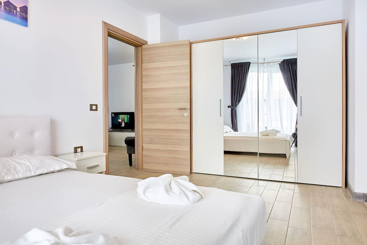A hotel room with a large bed, a bedside table, a TV, and a wardrobe with a mirror.