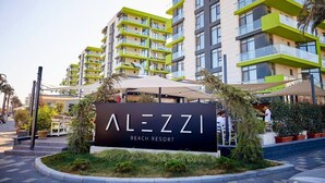 Ein modernes Gebäude mit Balkonen und einem Schild, auf dem "ALEZZI BEACH RESORT" steht.