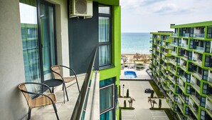 Ein Balkon mit Korbstühlen, einem Pool und Meerblick.