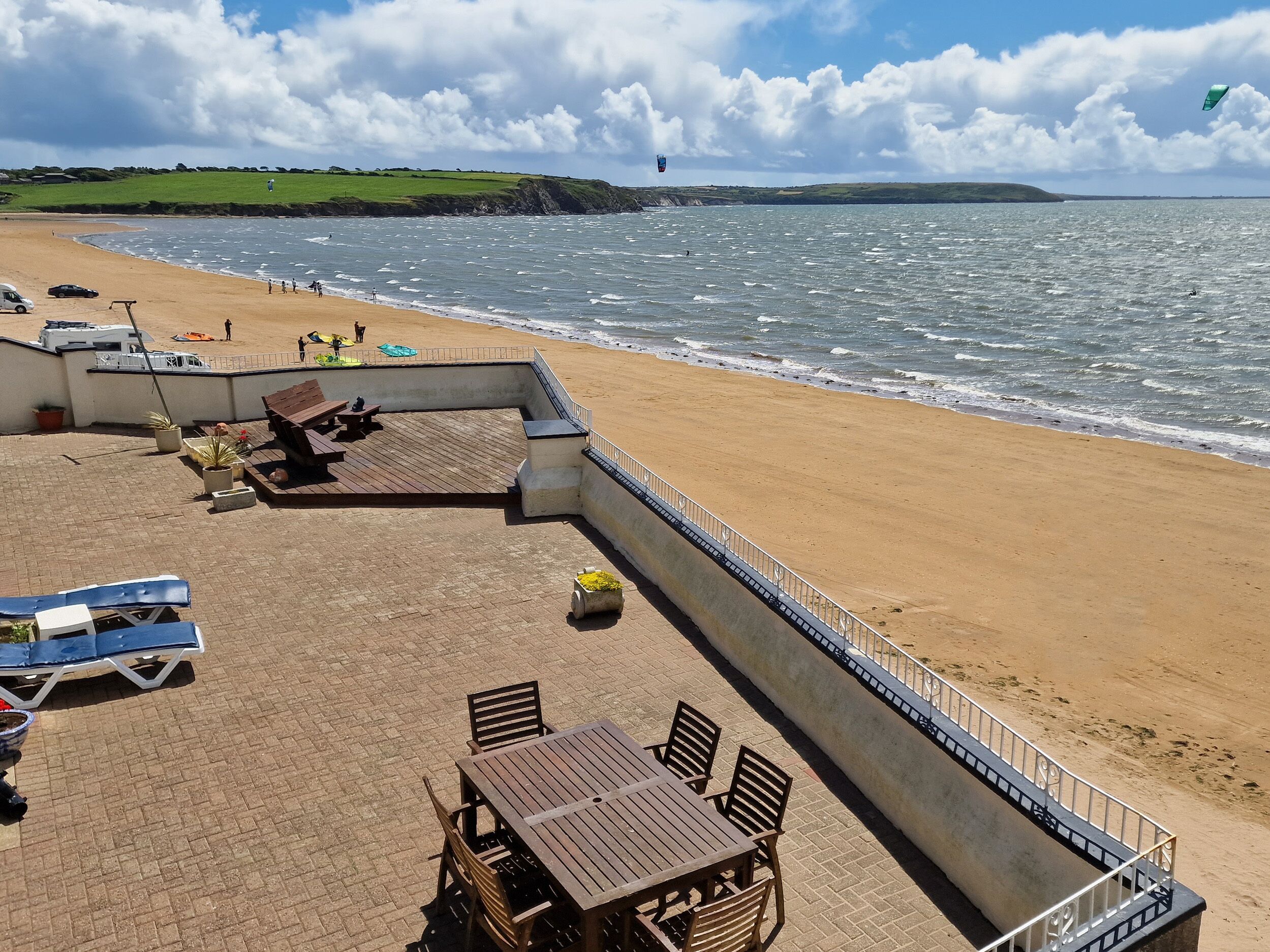 Eine Terrasse direkt am Strand mit Tisch und Stühlen, einem Grillbereich und Blick auf das Meer.
