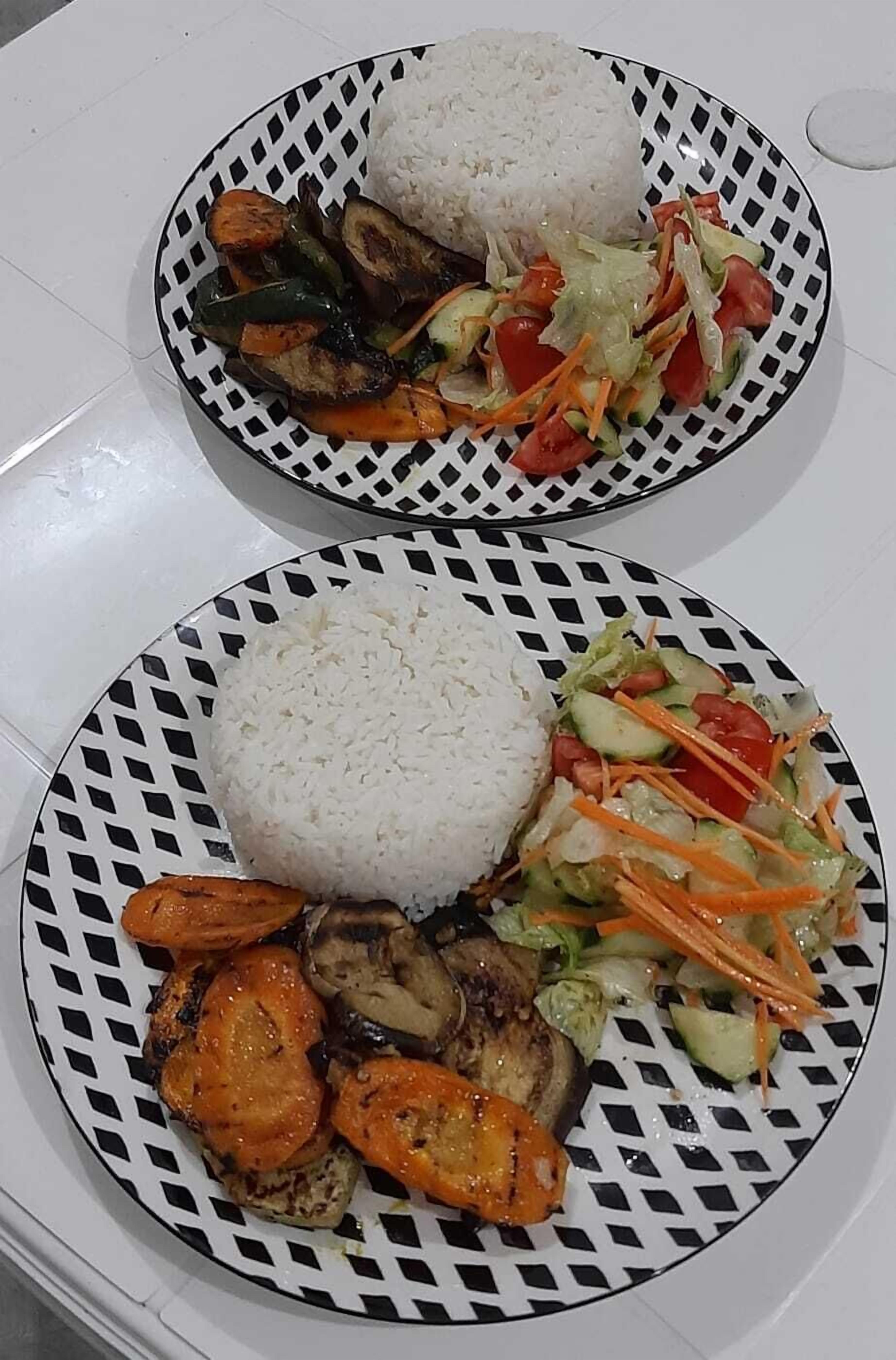 Duas porções de comida com arroz e legumes sobre uma mesa.