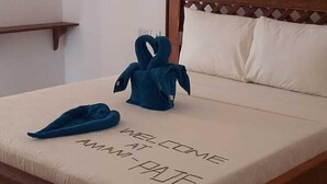 A neatly made bed with a pillow and a folded towel on the bed. - Amani Paje B&B (Paje)