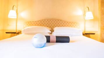 Une chambre d’hôtel avec un lit bien fait, deux lampes de chevet et un tapis de yoga.