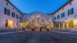 A dome-shaped structure with a geometric pattern, surrounded by a courtyard with tables and chairs.