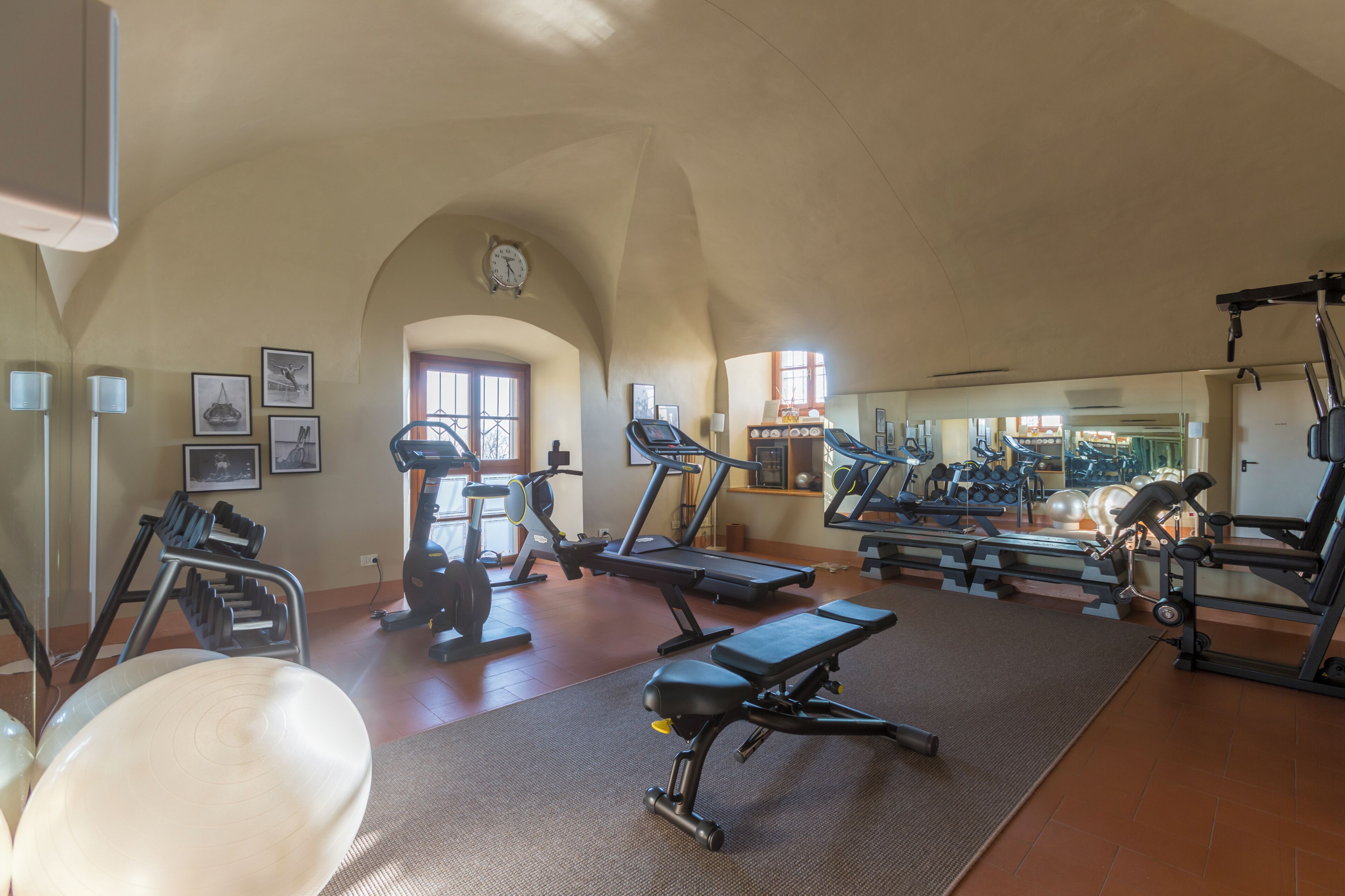 A gym with treadmills, weight machines, and a mirror wall.