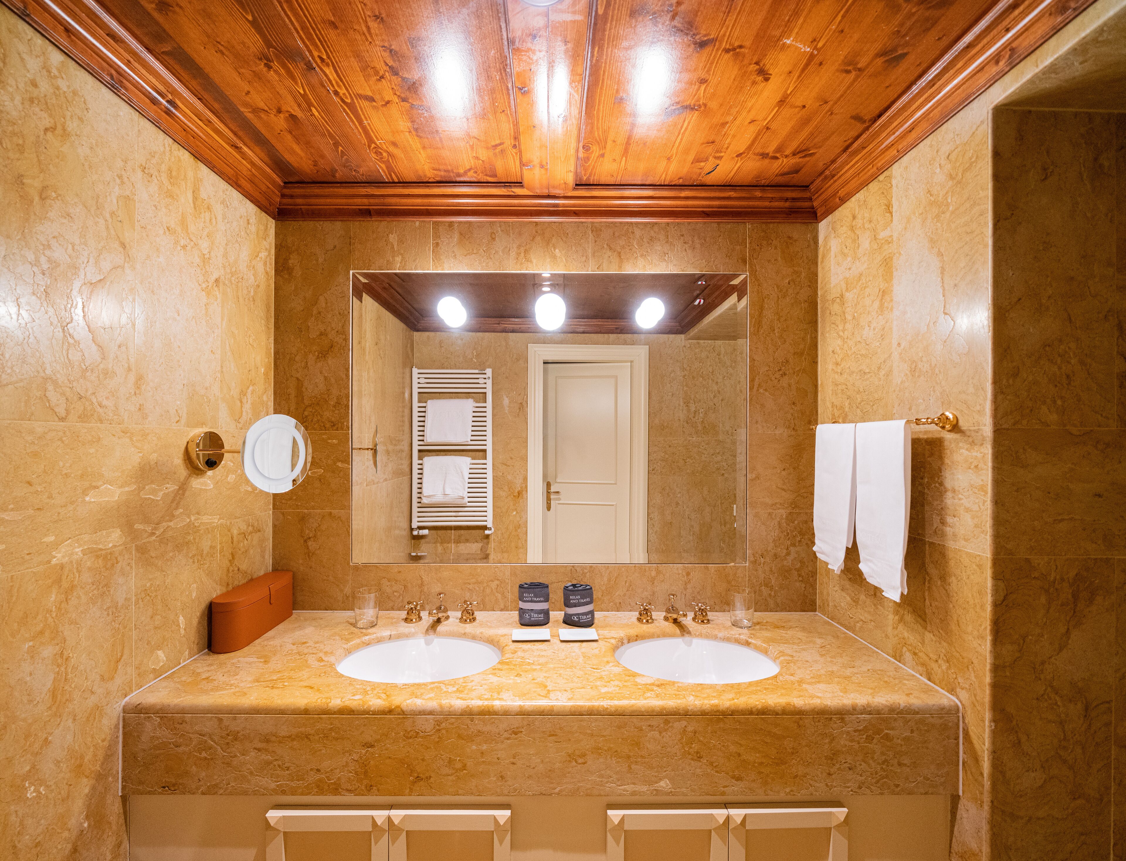 Un baño con dos lavamanos, un espejo, toallero y techo de madera.