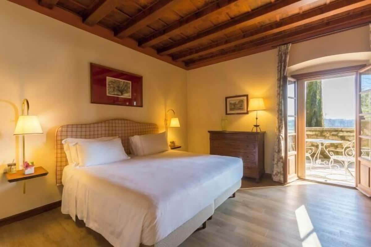 Une chambre à coucher avec un lit, des lampes de chevet, une commode et un balcon avec vue.