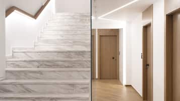 Una escalera de mármol conduce a una plataforma, con suelo de madera y una puerta al final del pasillo.