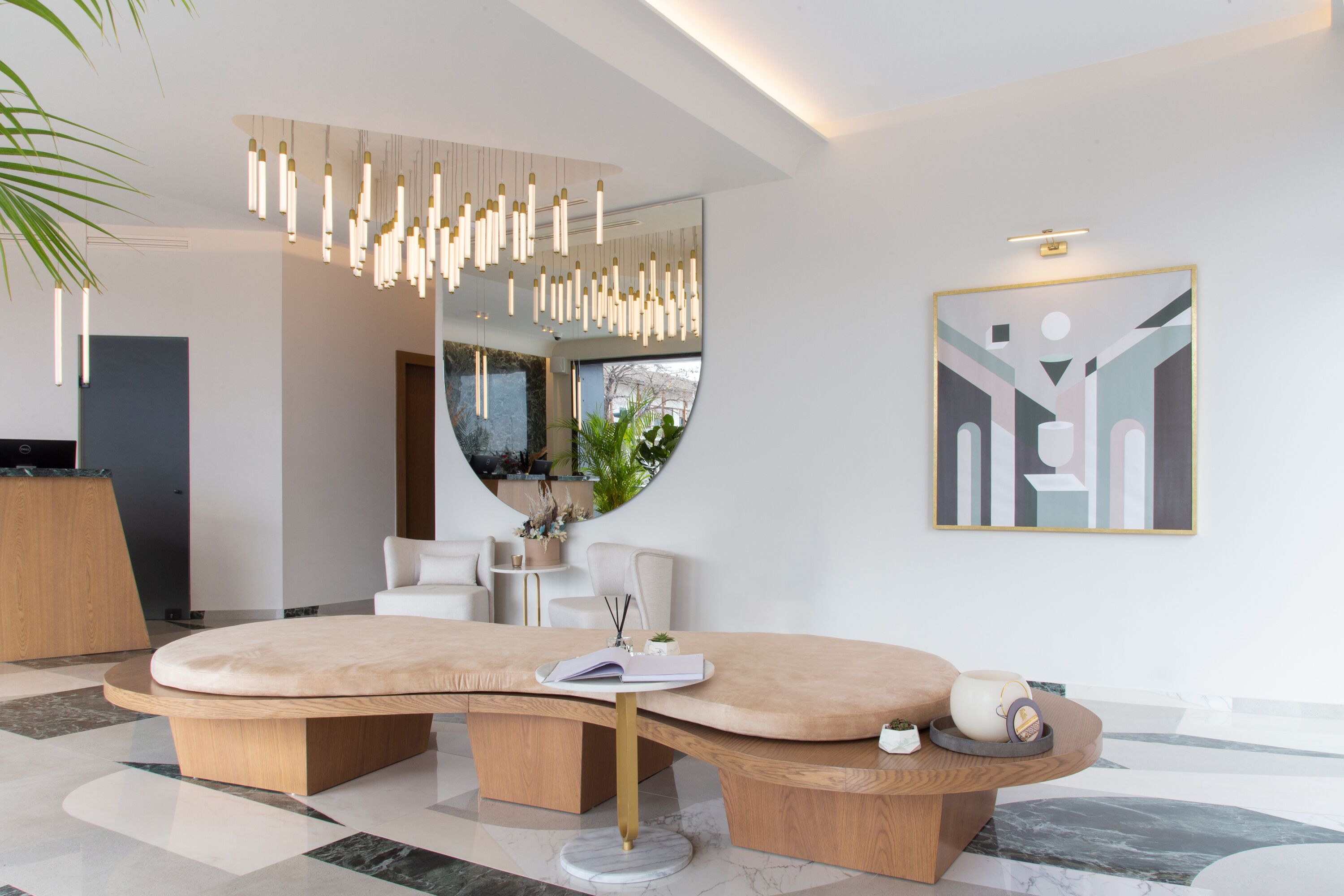 A modern interior with a curved wooden table, a hanging light fixture, and a framed abstract artwork on the wall.