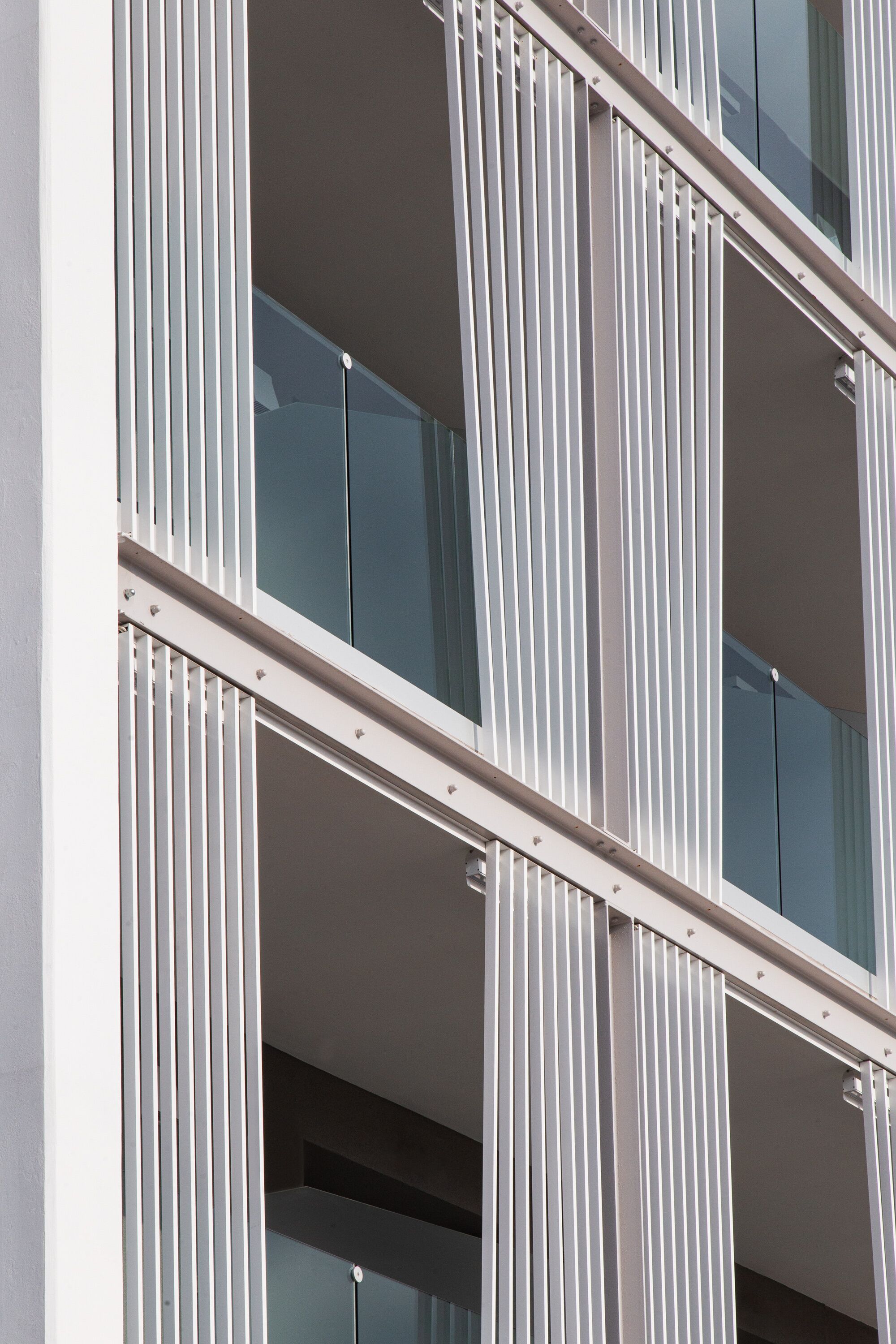 A modern building facade with vertical white panels and large windows.