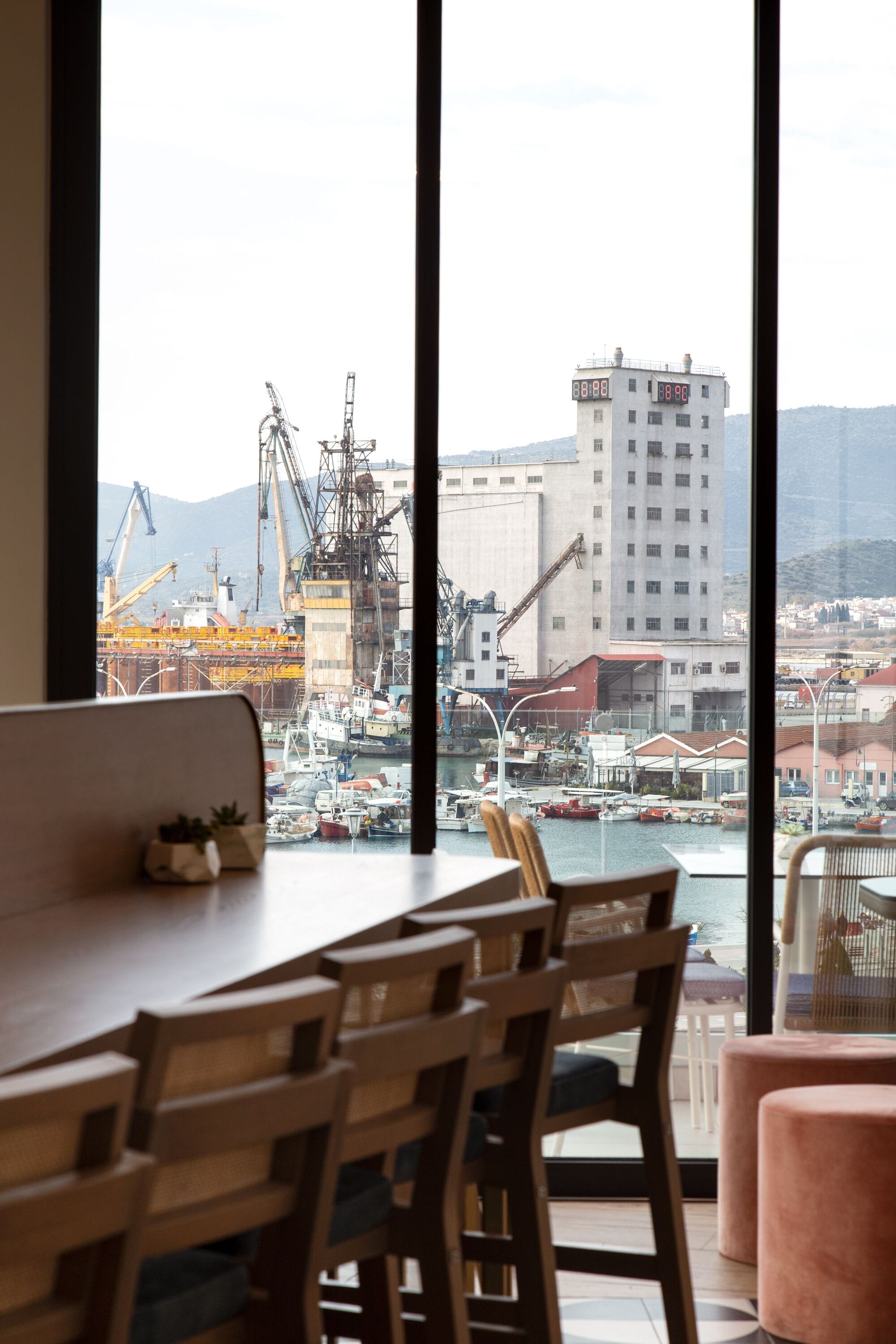 Un comedor con vistas al puerto, que incluye una mesa y sillas, y un amplio ventanal con vistas al agua y edificios.