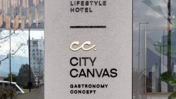 Une enseigne verticale indiquant les numéros 10, Lifestyle Hotel, City Canvas, Gastronomy Concept et Manthos Hotel Collection.